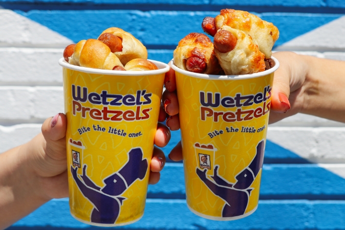 Two cups of Wetzel's dog bites being held 